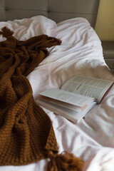 Lazy time in bed. Opened book lying on white blanket. Stay home during coronavirus covid-19...