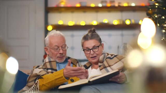 Senior couple reading book during christmas evening
