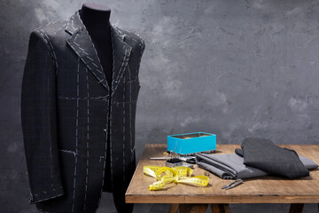 suit jacket on male tailor mannequin and sewing tools