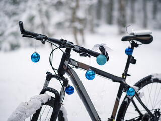 Mountain Bike in a snow-covered forest. Painted instead of a Christmas tree with blue holiday balloons and garlands.