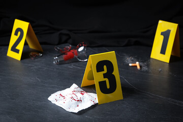 Bloody napkin and crime scene marker on black slate table