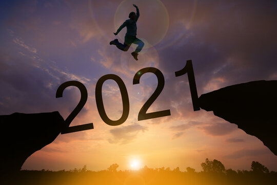 Happy new year Silhouette sunset background.A man are jumping over to cliff and jump across 2021 word.Photo Silhouette and new year.