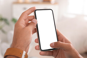 Man using mobile phone with empty screen indoors, closeup