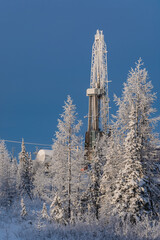 Winter landscape of a taiga forest with a drilling rig at the Northern oil and gas field....