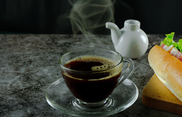 Coffee cups, transparent, with hot smoke, and bubbly, on a dark table.