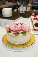 Obraz na płótnie Canvas White cake with pink flowers on golden tray