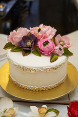 White cake with pink flowers on golden tray