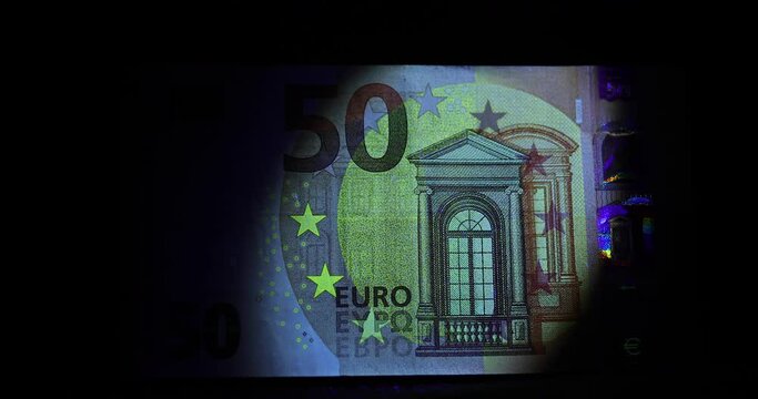 Fifty euro banknote in the ray of ultraviolet light with security signs watermark and other protection against fraud