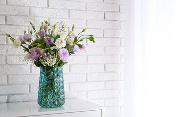 Bouquet of beautiful Eustoma flowers on table near white brick wall. Space for text
