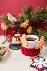 On a light wooden background, a Cup of tea and cookies in the form of butterflies with Christmas decorations . Close-up, copy space