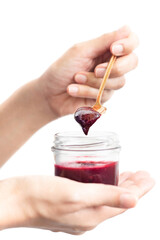 Woman hand holding a spoon with berry jam in jar in clipping path.