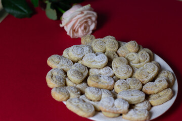 cookies on a plate and pink rose on red background
