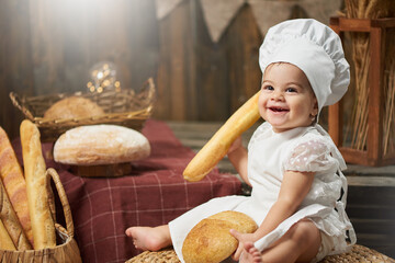 Happy baby baker holding bread and smiling