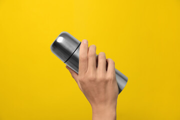 Woman holding modern thermos on yellow background, closeup