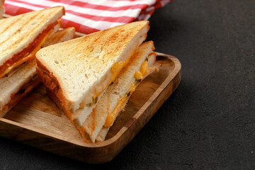 Sandwiches cut into halves on wooden cutting board with napkin