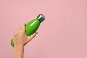 Woman holding modern green thermos on pink background, closeup. Space for text