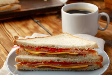 Toast sandwich and cup of coffee on napkin on wooden table