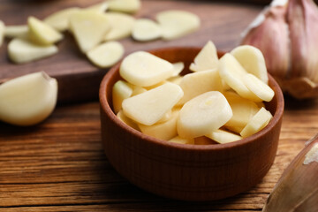 Fototapeta na wymiar Fresh chopped garlic in bowl on wooden table, closeup. Organic product