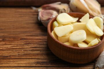 Fototapeta na wymiar Fresh chopped garlic in bowl on wooden table, closeup with space for text. Organic product