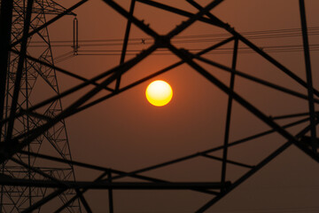 A nice view of the sunset behind the electric tower and tree