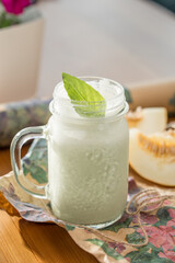 healthy smoothie with mint in glass mason jar on wooden table at cafe
