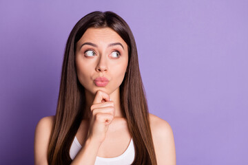 Photo portrait of pouting thinking girl touching face chin with finger looking at blank space isolated on vivid purple colored background