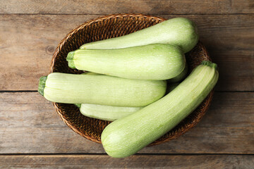 Basket of ripe zucchinis on wooden table, top view