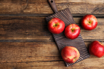 Fresh ripe red apples on wooden table, flat lay. Space for text
