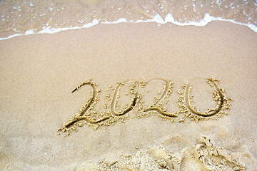 2020 text painted on the sand. Water washed away the text on the beach. The 2021 year is coming