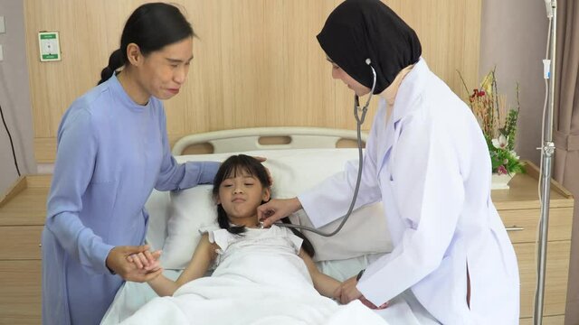 Arab doctor woman examining asian girl patient body by stethoscope with mather in hospital