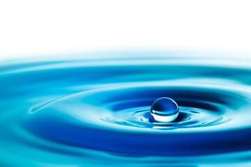 Dark blue water droplets splash in the water surface  close up. Creating a perfect water wave