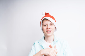 Cute Caucasian boy in a Santa Claus hat and blue polo shirt is smiling on a white background