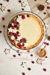 Delicious Christmas cheesecake with cranberries and cookies stars on a white table