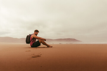 Lonely guy on red sand beach