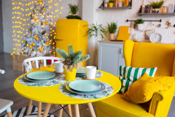Trendy fashion luxury interior design in Scandinavian style of studio apartment with bright yellow furniture and decorated with new year lights.