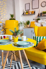 Trendy fashion luxury interior design in Scandinavian style of studio apartment with bright yellow furniture and decorated with new year lights.