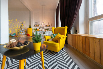 Trendy fashion luxury interior design in Scandinavian style of studio apartment with bright yellow furniture and decorated with new year lights.