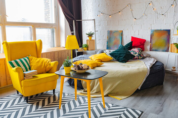 Trendy fashion luxury interior design in Scandinavian style of studio apartment with bright yellow furniture and decorated with new year lights.