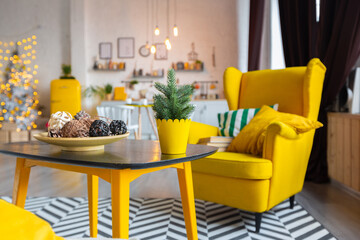 Trendy fashion luxury interior design in Scandinavian style of studio apartment with bright yellow furniture and decorated with new year lights.