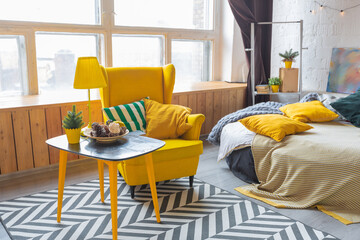 Trendy fashion luxury interior design in Scandinavian style of studio apartment with bright yellow furniture and decorated with new year lights.