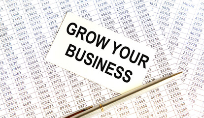 Obraz premium On the business card the text of GROW YOUR BUSINESS, all on the background of reports.
