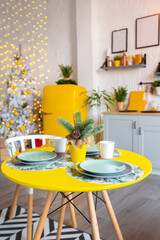 Trendy fashion luxury interior design in Scandinavian style of studio apartment with bright yellow furniture and decorated with new year lights.