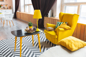 Trendy fashion luxury interior design in Scandinavian style of studio apartment with bright yellow furniture and decorated with new year lights.