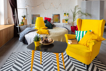 Trendy fashion luxury interior design in Scandinavian style of studio apartment with bright yellow furniture and decorated with new year lights.