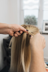 Fototapeta premium Girl in a hair salon, stylist make hair style for client in Woman's Hair In Hairdresser Salon, close view of hands, spikelet 