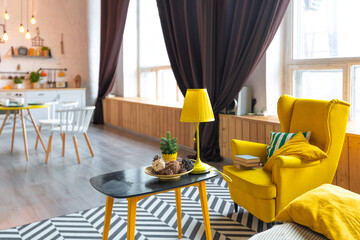 Trendy fashion luxury interior design in Scandinavian style of studio apartment with bright yellow furniture and decorated with new year lights.