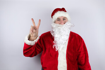Fototapeta na wymiar Man dressed as Santa Claus standing over isolated white background showing and pointing up with fingers number two while smiling confident and happy