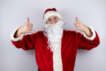 Fototapeta na wymiar Man dressed as Santa Claus standing over isolated white background shouting with crazy expression doing rock symbol with hands up