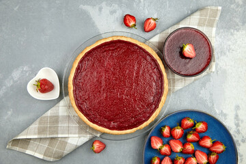 Strawberry pie with fresh berries and strawberry jam on grey concrete background, top view