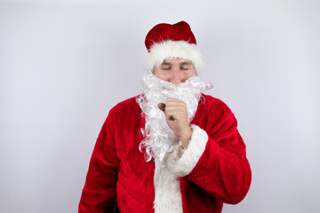Man dressed as Santa Claus standing over isolated white background with his hand to his mouth coughing